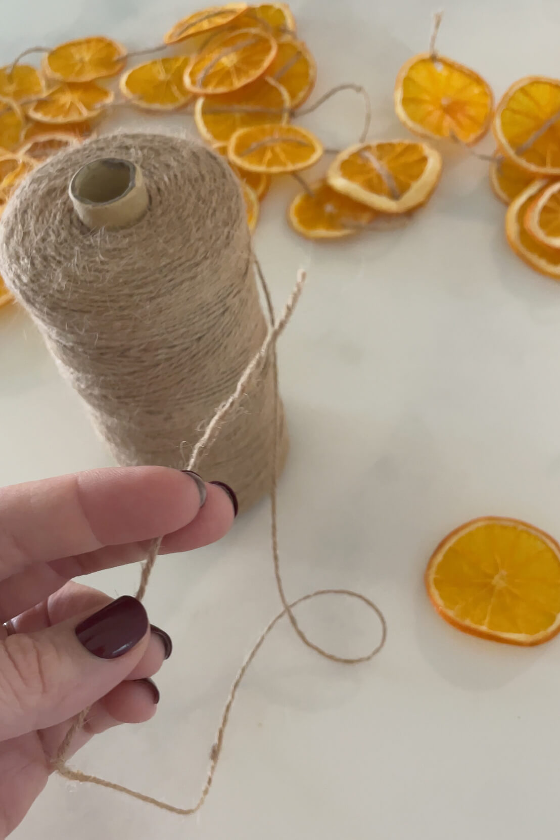 Using twine and a needle to make an orange slice garland.